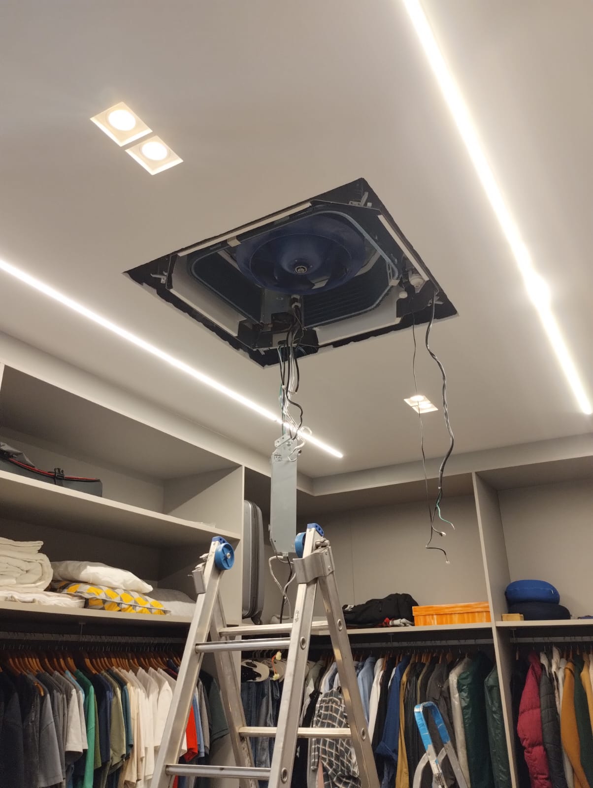 ar-condicionado cassete parcialmente instalado no teto rebaixado com fita de LED, sobre uma escada em um close